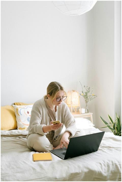 A woman working remotely from home sitting on a be