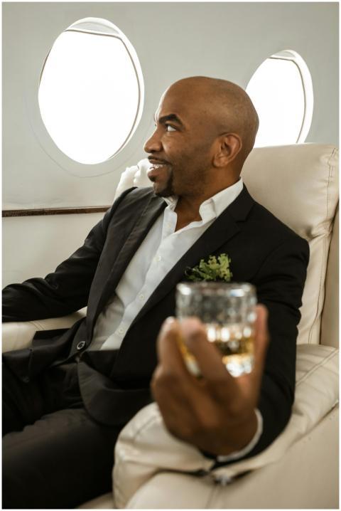 Man relaxing with drink in a private jet, exuding