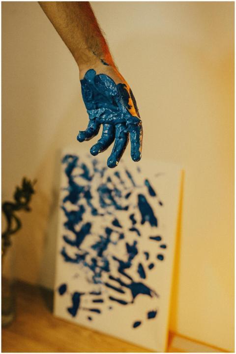 Close-up of a painted hand above an abstract blue