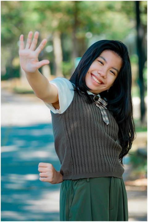 Joyful young girl waving cheerfully on a sunny day