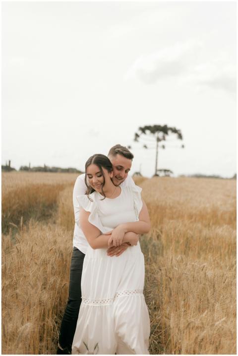 A couple embraces in a serene wheat field, highlig