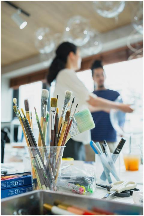 Art supplies in focus with blurred figures backgro