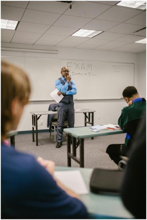 A professor stands attentively in a classroom obse