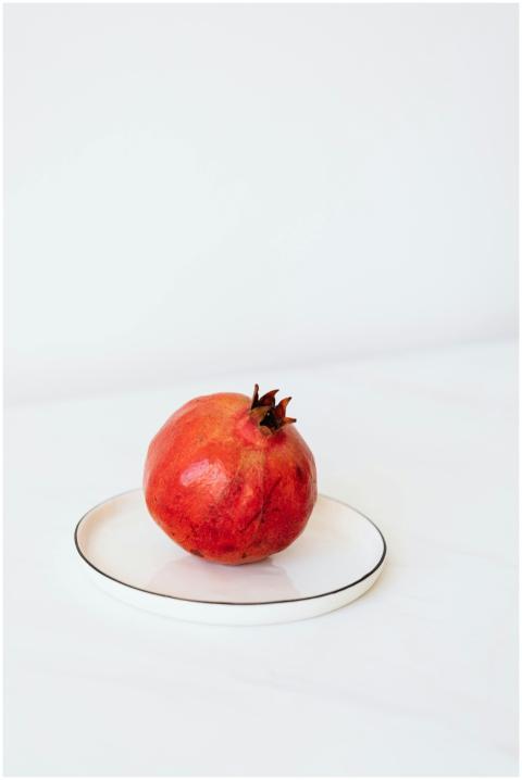 Whole ripe pomegranate placed on white metal plate