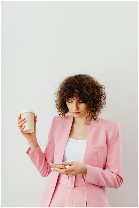 Confident woman in a pink blazer holding coffee an