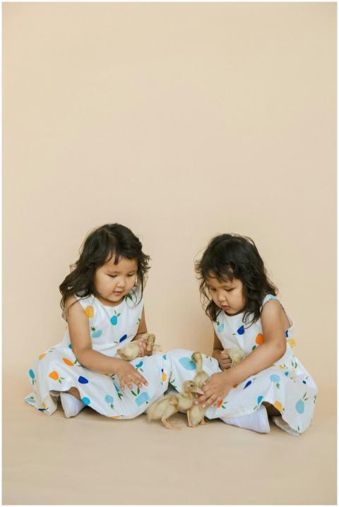 Adorable twin girls in polka dot dresses playing w
