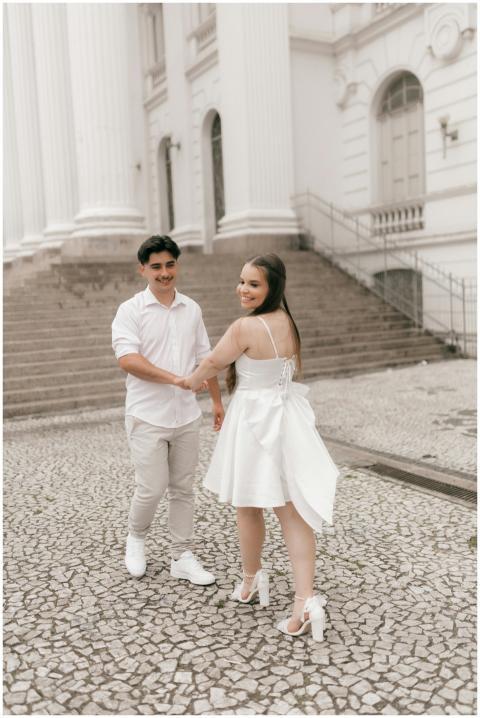 A happy couple in white attire shares a moment nea