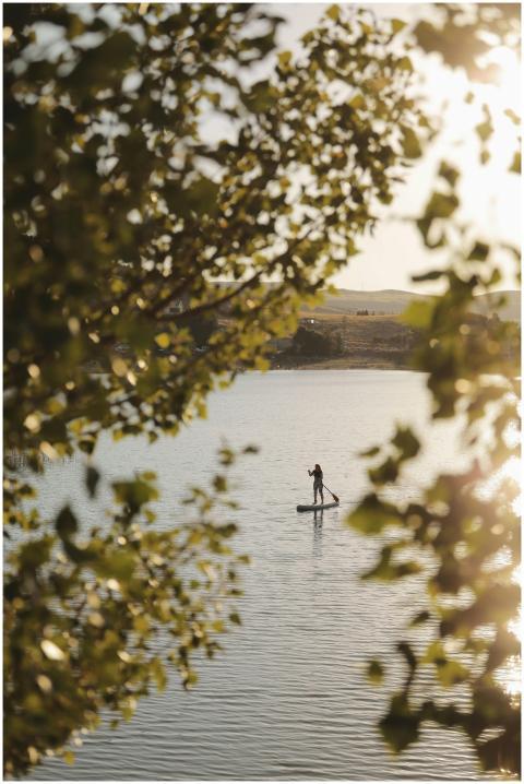A lone paddleboarder enjoys a peaceful ride on a l
