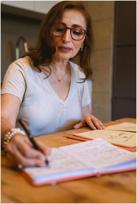 A senior woman with glasses writing in a notebook