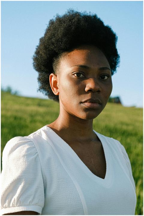 Elegant portrait of a woman in a sunlit grassy fie