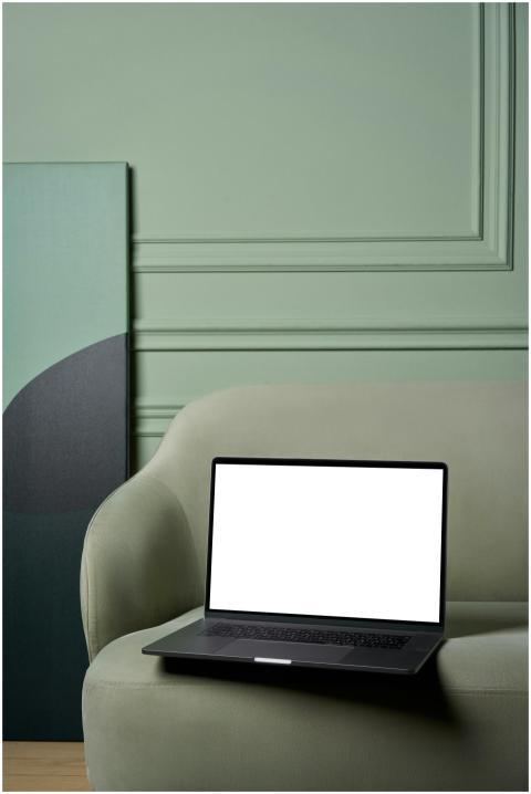 Laptop with white screen placed on soft sofa with