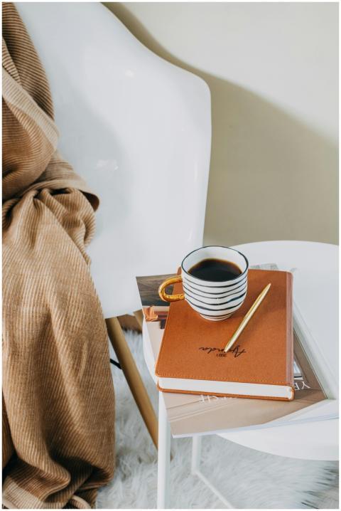 A cozy setup featuring coffee and a journal on a m