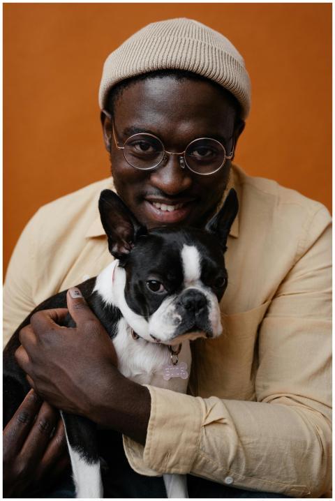 A cheerful man embraces his Boston Terrier in a wa