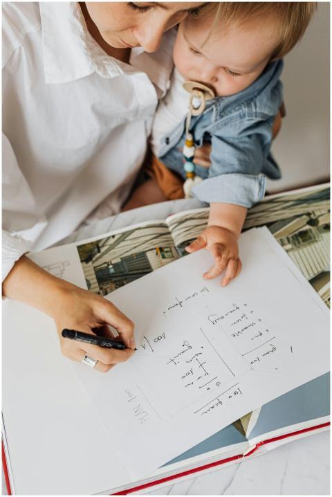 A mother writing while holding her baby in a cozy