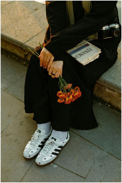 A person sits on a bench holding flowers and a new