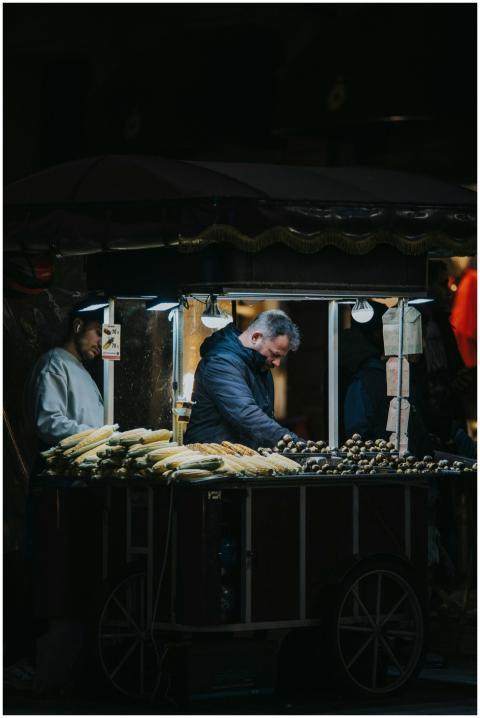 A street vendor serves grilled corn from a cart un