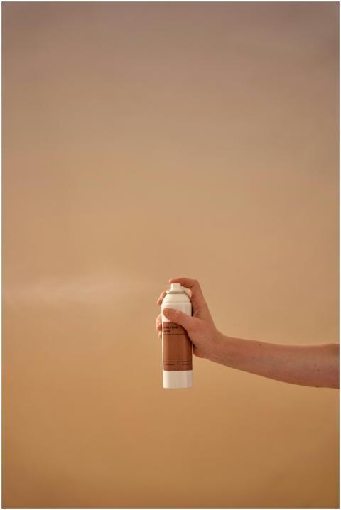 A clean studio shot of a hand holding a sunscreen