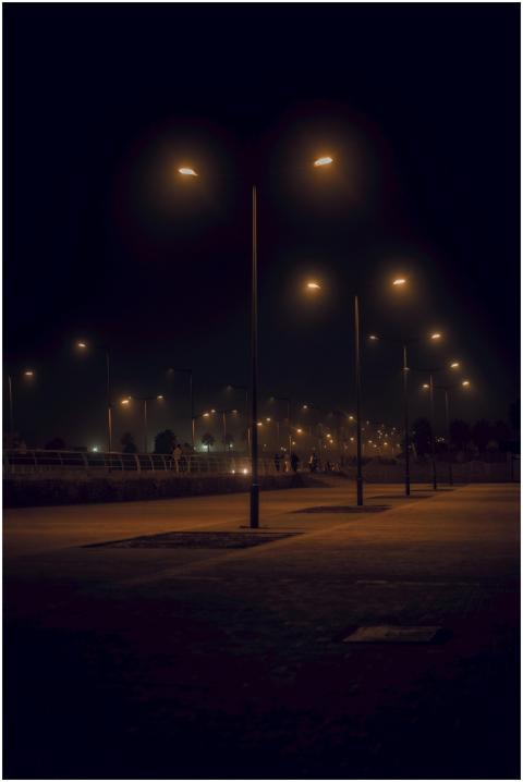 A moody, dimly lit street scene with rows of glowi
