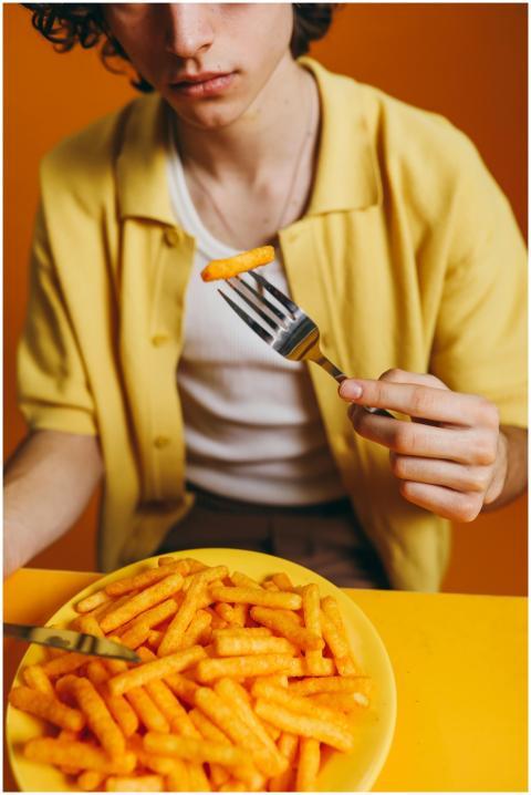 Young man in yellow attire enjoys a crispy potato