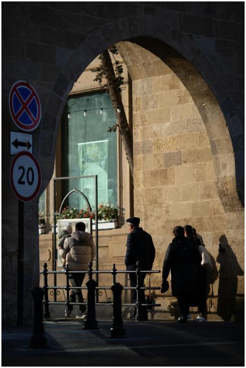 A group of people walking under a stone archway in