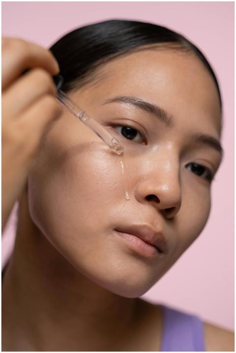 Close-up of a woman applying skincare serum with a