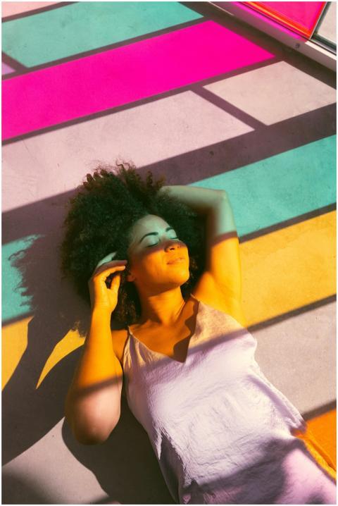 Woman relaxing on a colorful sunlit floor with sha