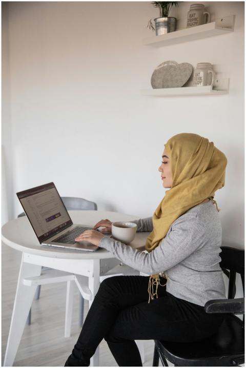 Side view of smiling young Muslim freelancer sitti
