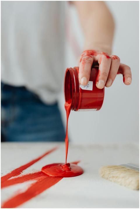 Artistic image featuring a hand pouring red paint