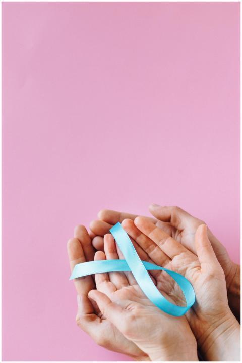 Close-up of hands holding a blue awareness ribbon