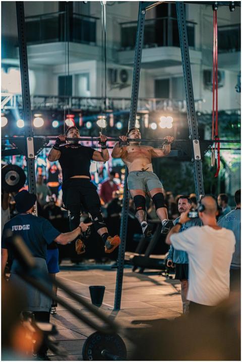 Male athletes perform pull-ups at an outdoor night