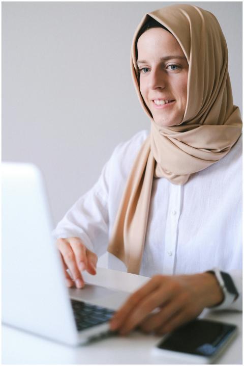 A woman in a hijab smiling while working remotely