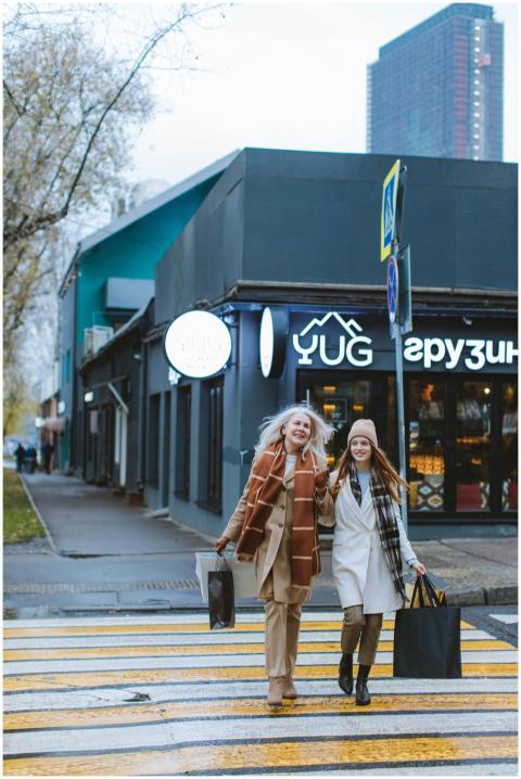 Fashionable women with shopping bags crossing an u