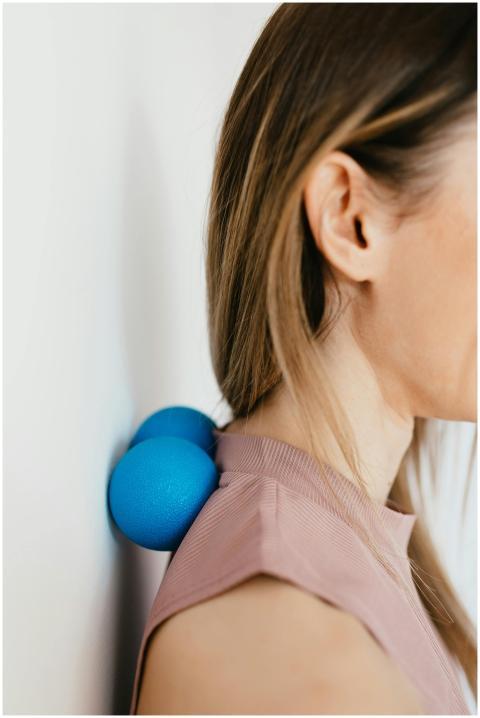 Side view of a woman using blue massage balls agai