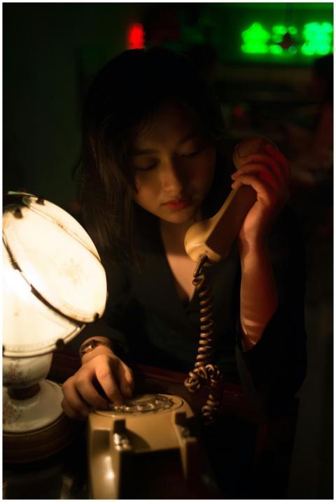 A dimly lit portrait of an Asian woman using an an