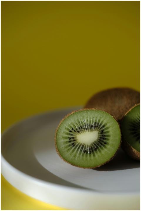 Close-up of sliced kiwi on a white plate against a