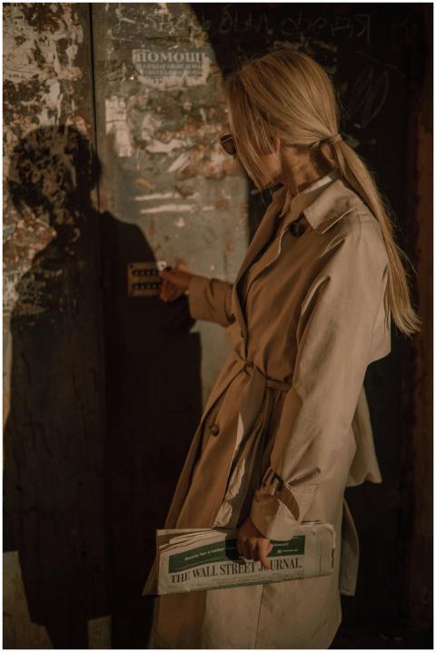 A woman in a trench coat holds The Wall Street Jou