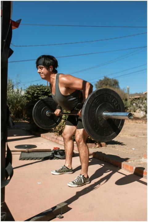 Young man lifting barbell outdoors during a workou