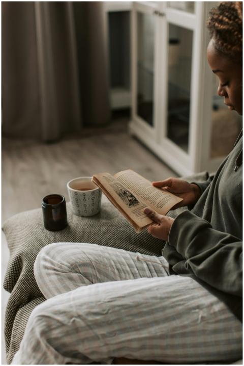 Woman reading at home with a warm cup of tea and c