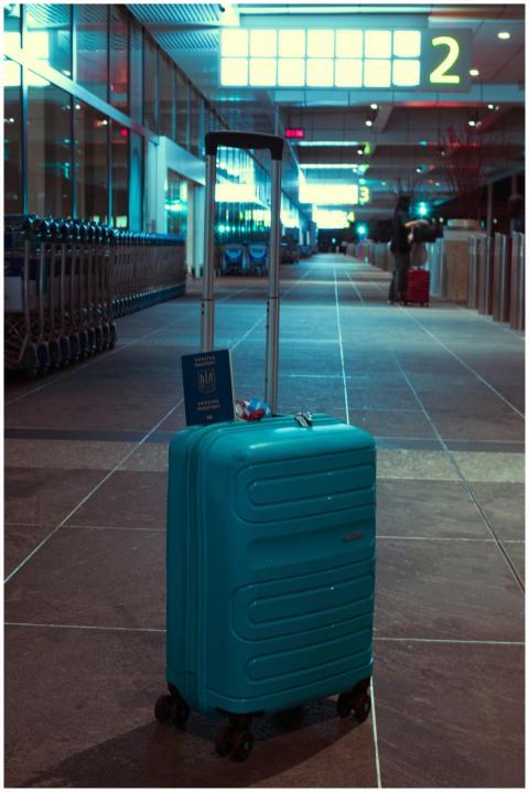 A blue suitcase with a passport in an empty airpor