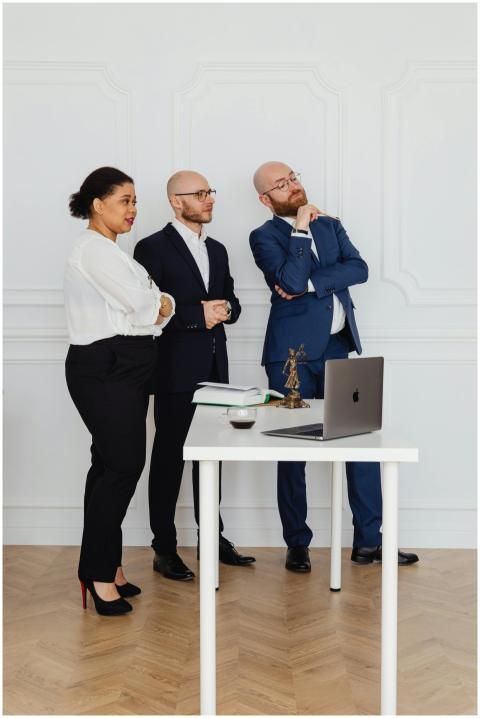 Three business professionals standing around a des