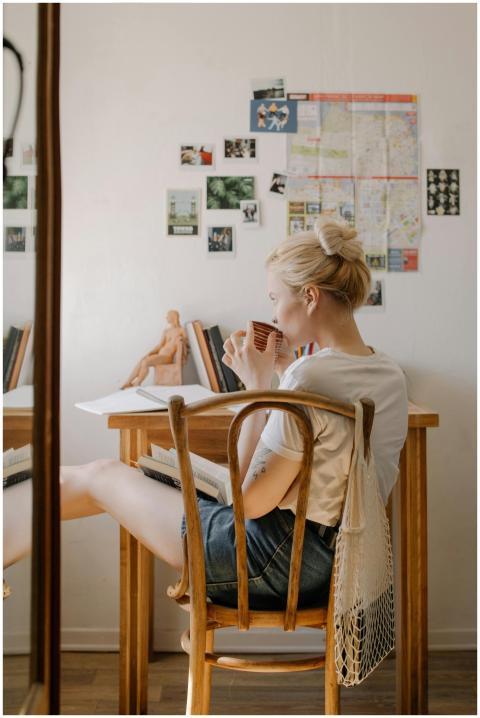 Back view of a blonde woman sipping tea in a cozy