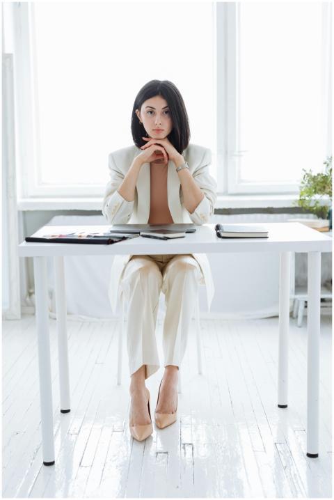 Elegant businesswoman in a white suit sitting at o