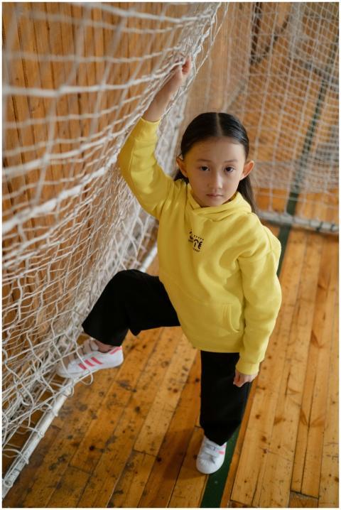 Young girl in yellow hoodie posing with a net in a