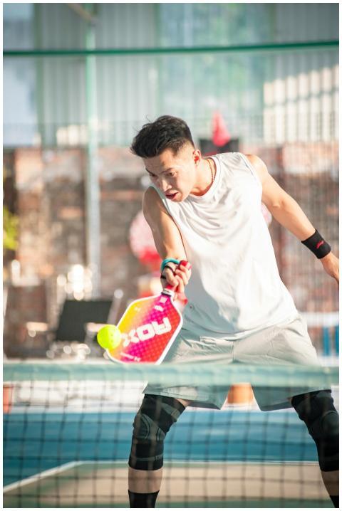 Energetic young man playing pickleball on an outdo