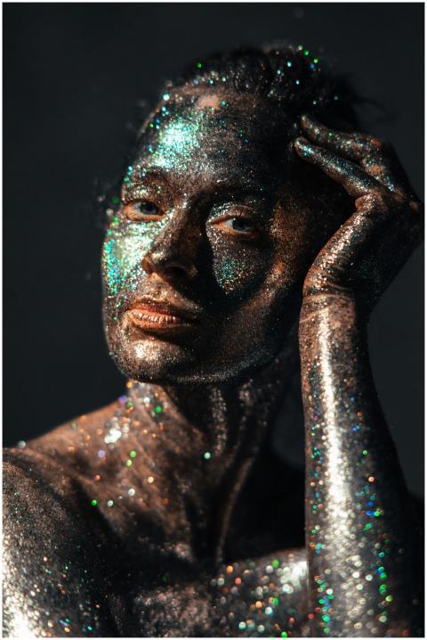 A woman posing with glitter-covered skin in a stud