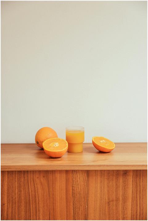 Glass of fresh orange juice with whole and sliced