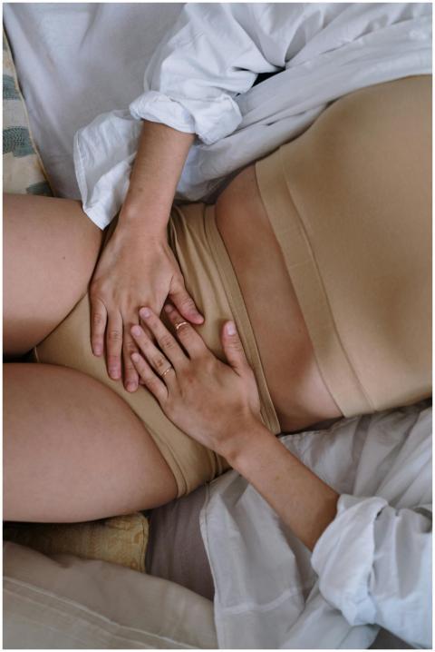 A woman holding her stomach, depicting menstrual o