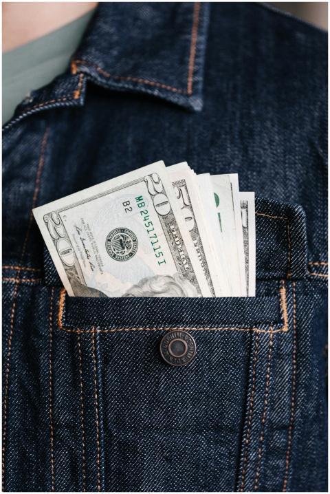 Close-up of US dollar bills in a denim jacket pock