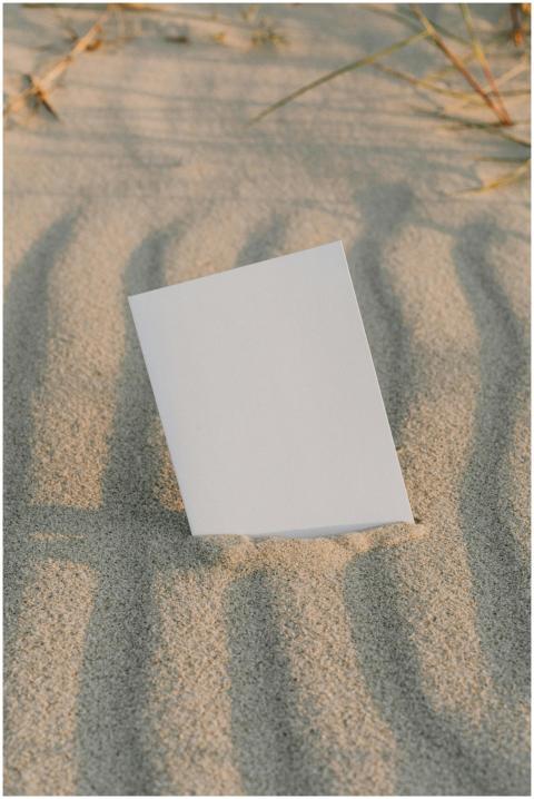 A blank white card standing on a textured sandy su