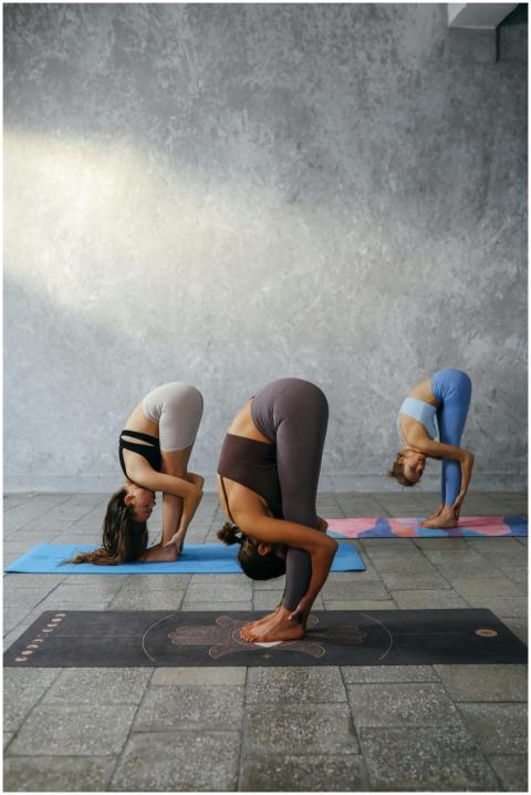 Three women performing yoga poses on mats in a cal